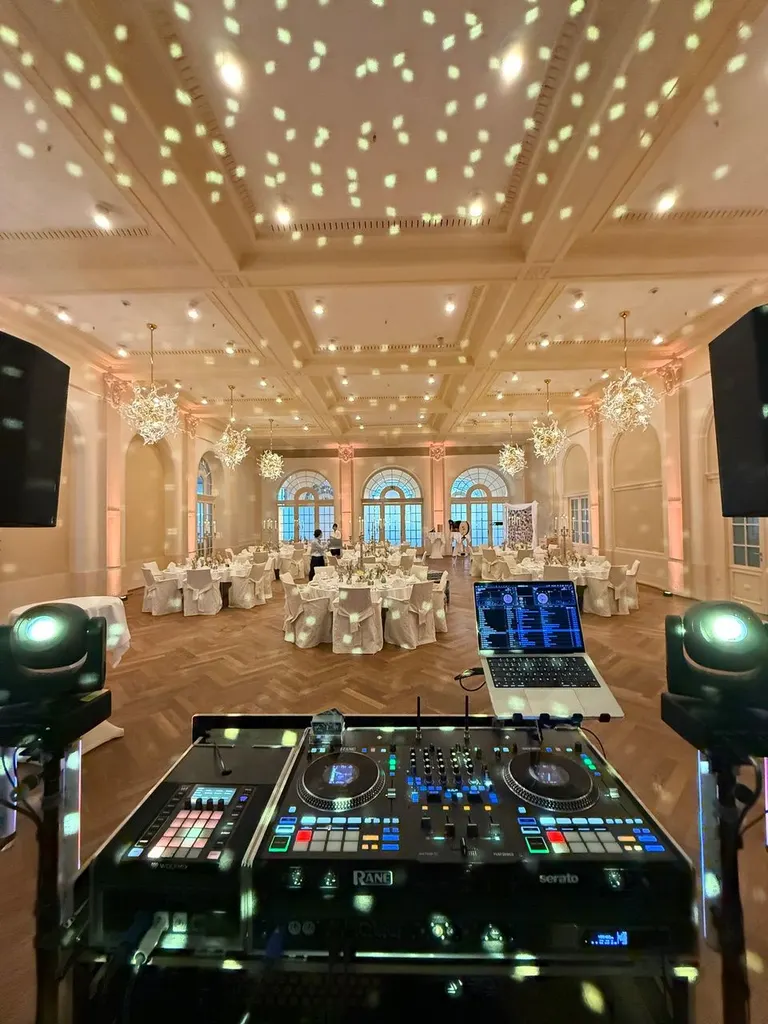 Blick über den DJ-Controller in den Festsaal mit Lichtpunkten an der Decke