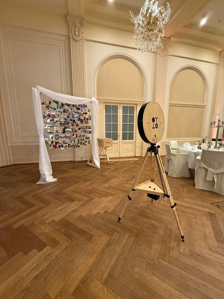 Fotobox auf einem Holzstativ vor einer Fotowand mit Stoffbögen im Festsaal des A-ROSA Travemünde