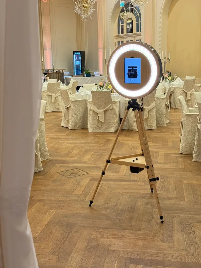 Fotobox mit Ringlicht auf einem Stativ im Festsaal mit gedeckten Tischen