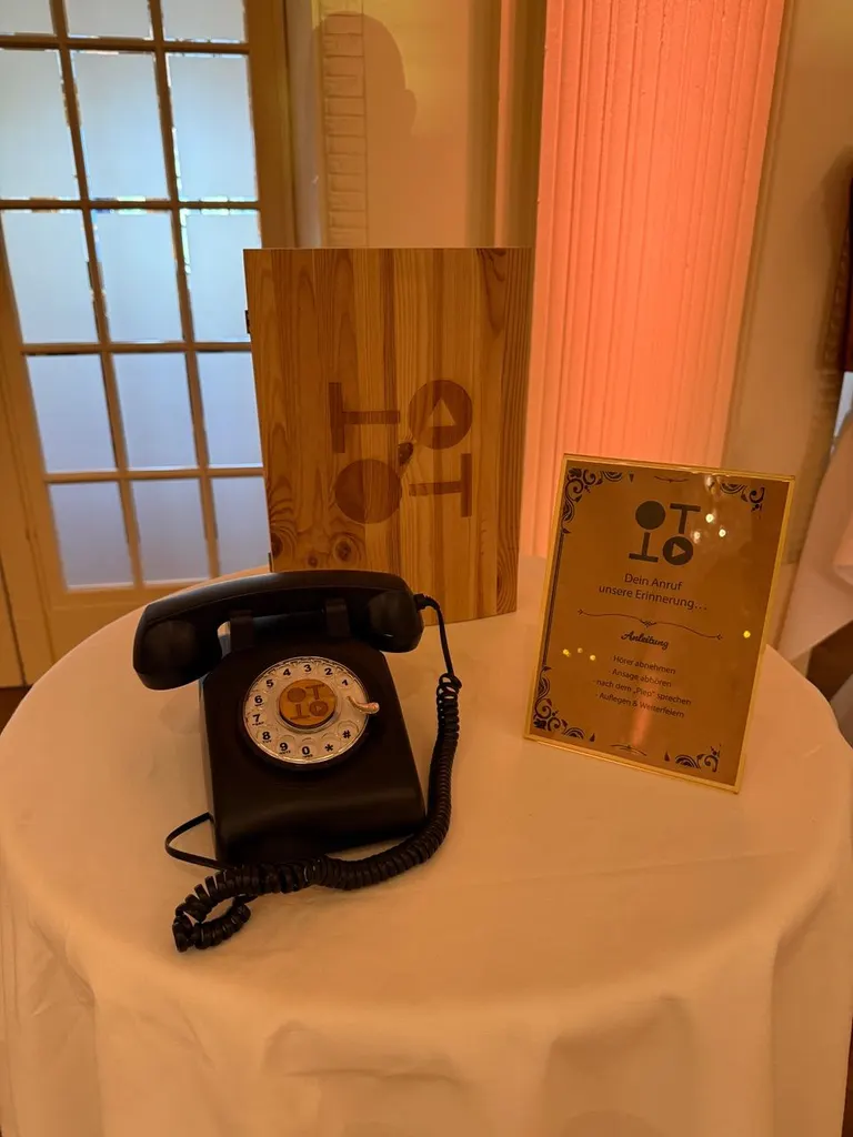 Altes Wähltelefon und Holztafel auf einem Tisch vor warm beleuchteter Wand