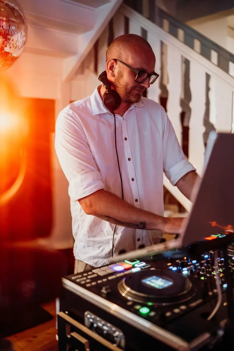 Eike Otto am DJ-Pult mit Laptop vor rotem Gegenlicht