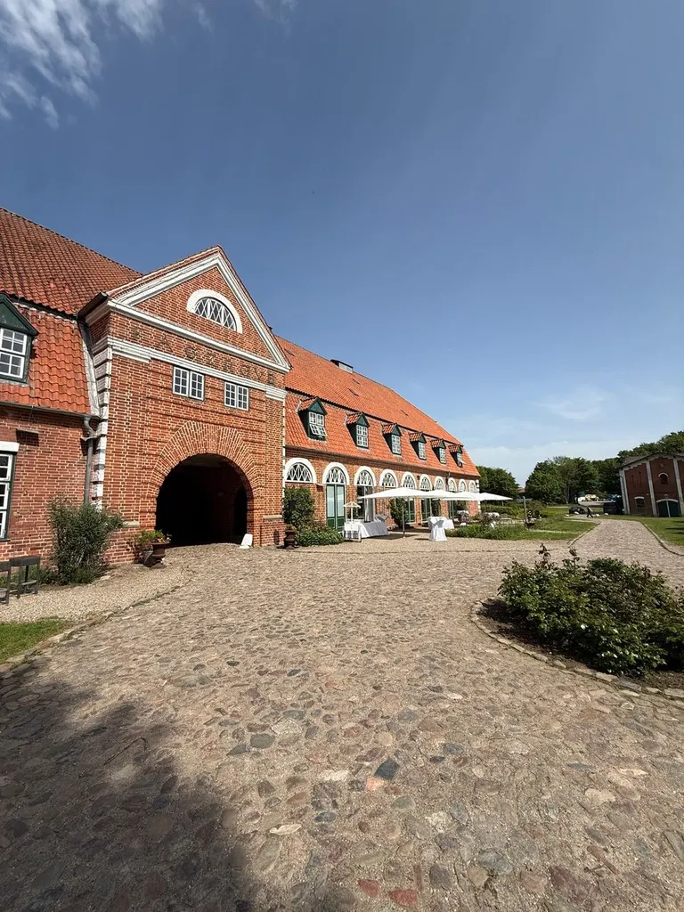 Innenhof von Gut Pronstorf mit Kopfsteinpflaster und Backsteingebäude mit Torbogen