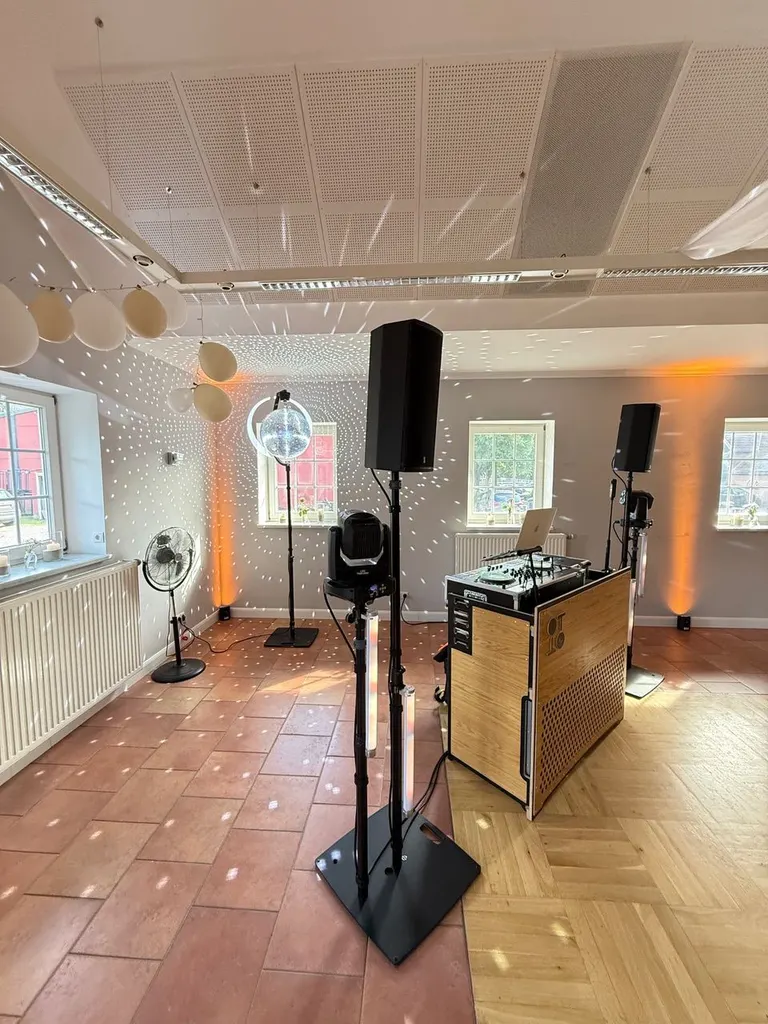 DJ-Pult aus Holz mit Lautsprechern und Moving Head im Festsaal von Gut Steinwehr, Lichtpunkte einer Discokugel auf dem Boden