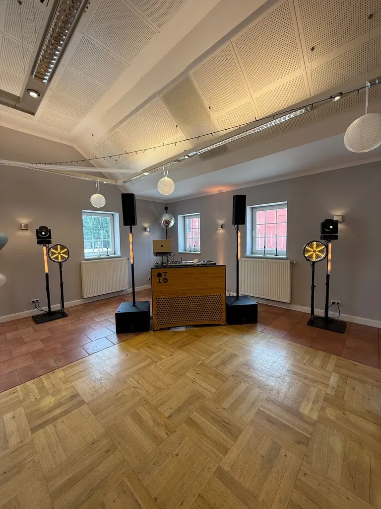 DJ-Pult, Lautsprecher und Lichtstative auf dem Parkett im Festsaal von Gut Steinwehr bei Tageslicht