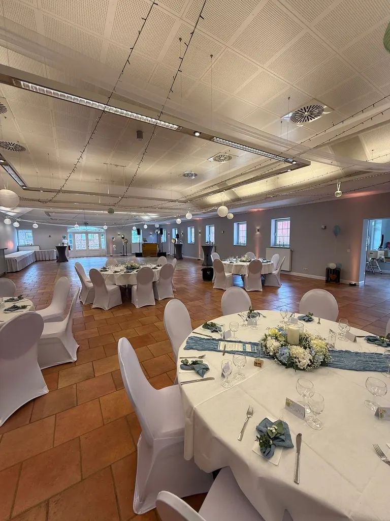 Festsaal von Gut Steinwehr mit gedeckten Tischen und Terrakotta-Boden