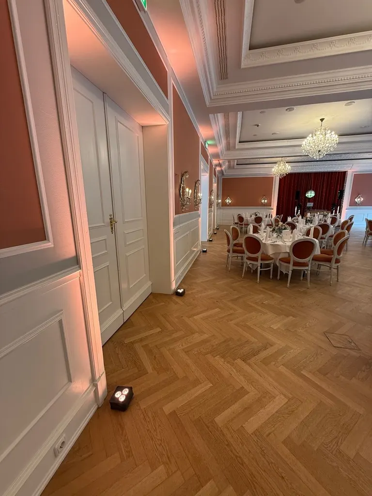 Festsaal im Strandhotel Glücksburg mit Flügeltüren, Fischgrätparkett und dezent beleuchteten Wänden