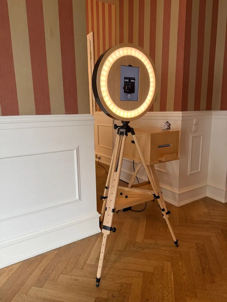 Fotobox mit Ringlicht auf einem Stativ vor einer gestreiften Tapete im Foyer